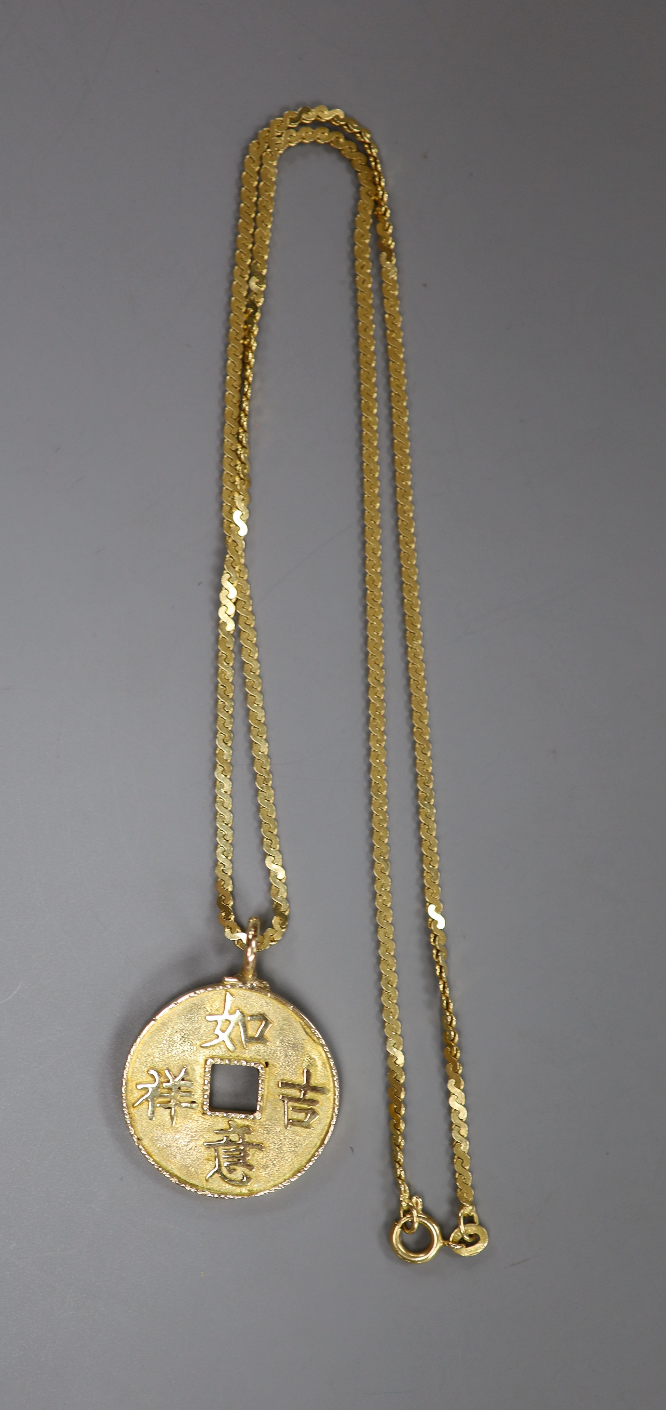 A Chinese yellow metal amulet, on an Italian Uno-A-Erre 750 chain, gross 13 grams.